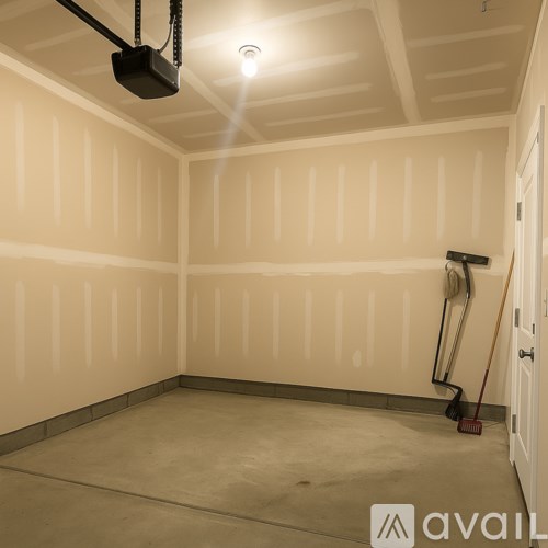 A room with a white wall and a broom on the floor.