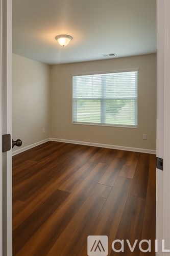 A room with wooden flooring and a window with blinds.