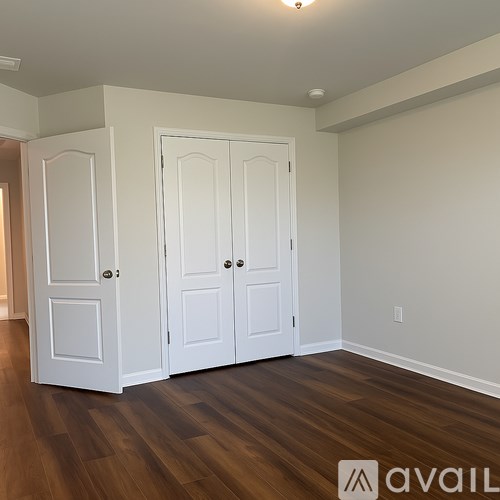 A room with two white doors and wooden floors.