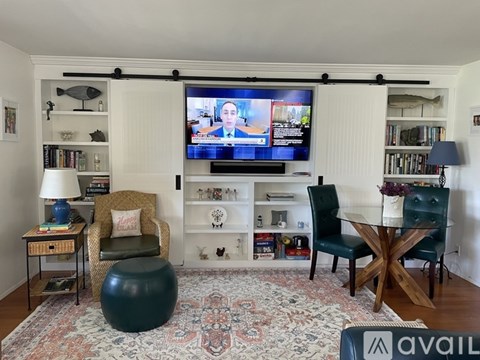 A living room with a television on the wall and a rug on the floor.