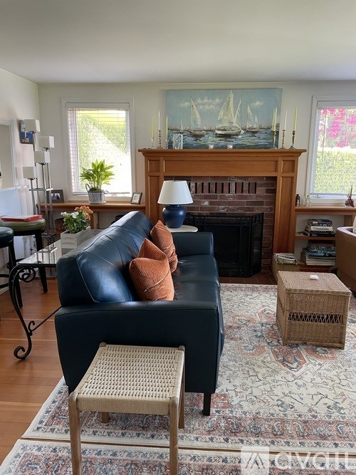 A living room with a black leather couch and a woven stool.