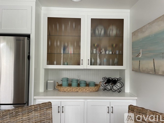 A kitchen with white cabinets and a painting on the wall.