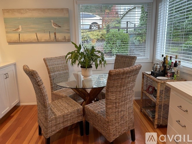 A dining room with a table and chairs and a painting of two birds on the wall.