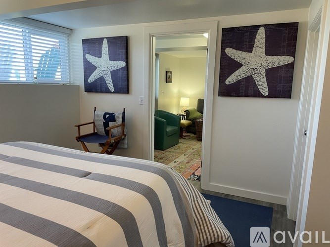 A bedroom with a bed, a chair, and two starfish pictures on the wall.