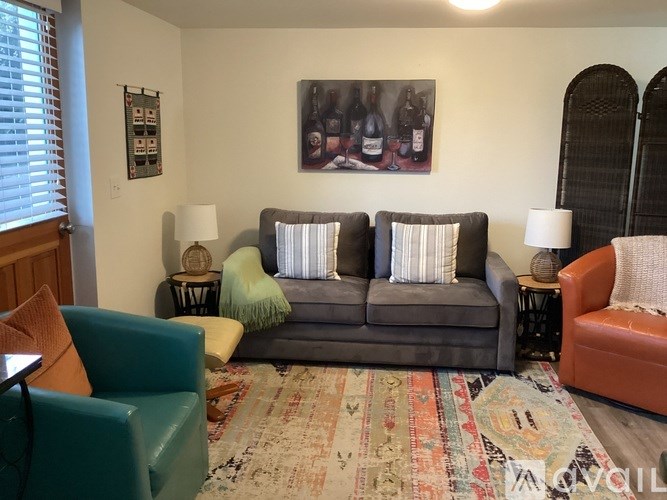 A living room with a grey couch and a rug.