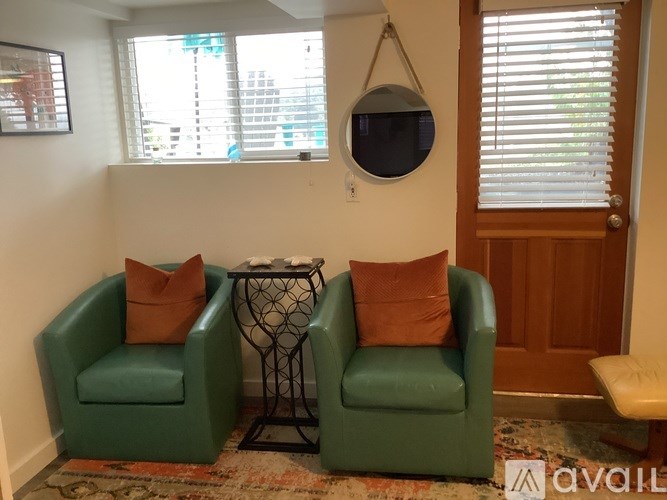 Two green chairs with orange pillows in a room.