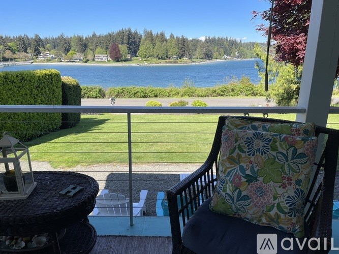 A balcony with a chair and a table overlooking a body of water.