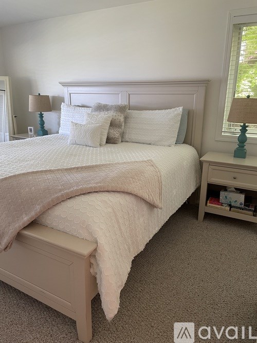 A bedroom with a large bed and two nightstands with lamps.