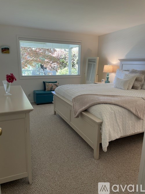 A bedroom with a large bed and a window with a view of trees.