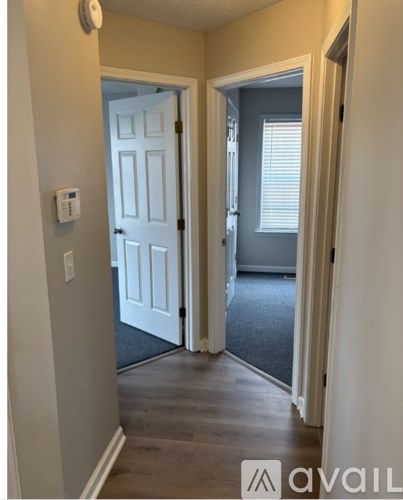 A room with a carpeted floor, a window with blinds, and a ceiling light.