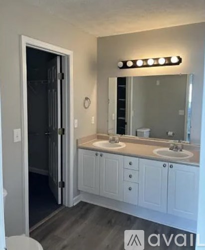A bathroom with a white vanity and a mirror with lights above it.