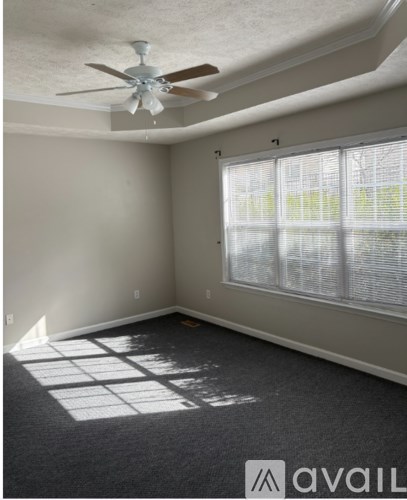 A room with a ceiling fan and a window with blinds.