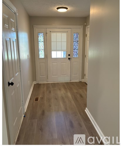 A hallway with a wooden floor and white walls.