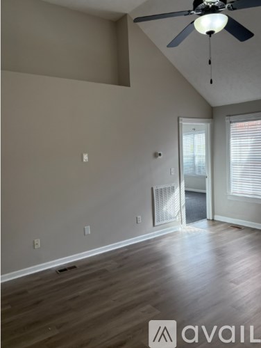 A room with a ceiling fan and wooden flooring.