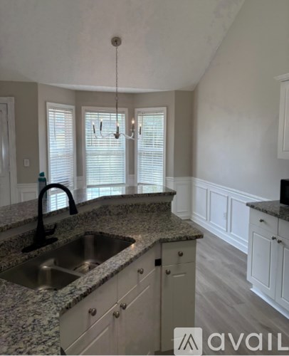 A room with a chandelier, two windows with blinds, and a wall with paneling.