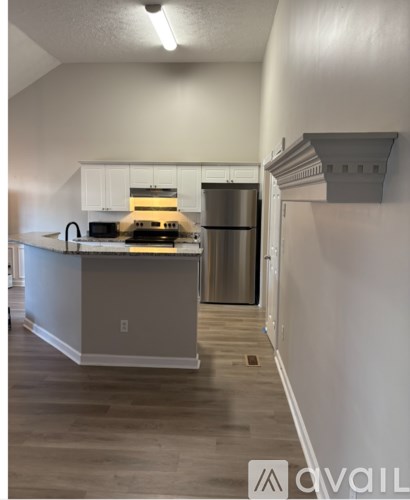 A kitchen with a stainless steel refrigerator and a wooden floor.