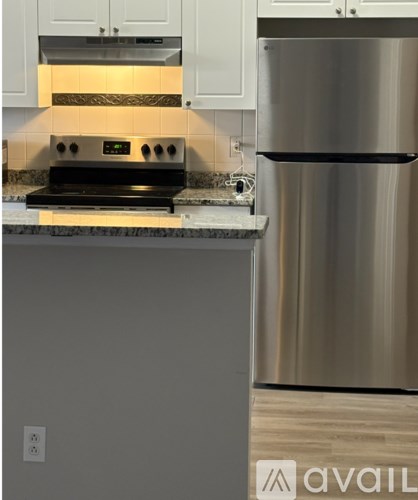 A modern kitchen with a stainless steel refrigerator and a black induction cooktop.
