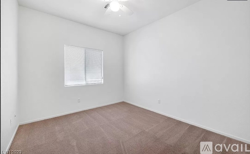 A room with a carpeted floor and a window with blinds.