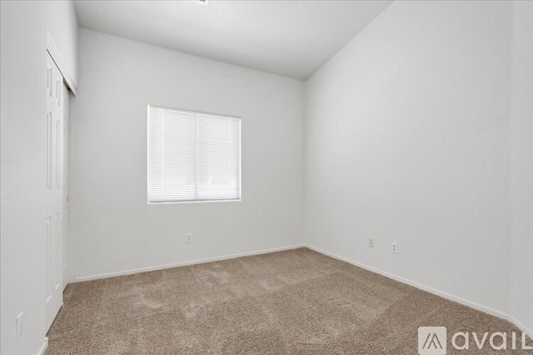 A room with a carpeted floor and a window with blinds.