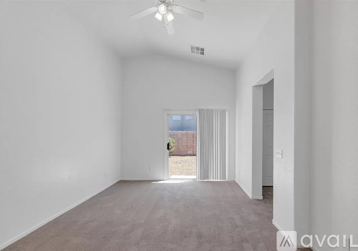 A spacious empty room with a ceiling fan and a door leading to a balcony.