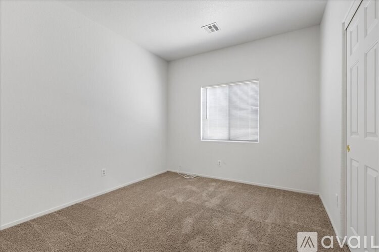 A room with a carpeted floor and a window with blinds.