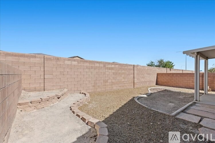 A backyard with a concrete patio and a wall made of bricks.