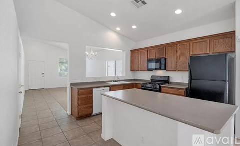 A kitchen with a black refrigerator and wooden cabinets.