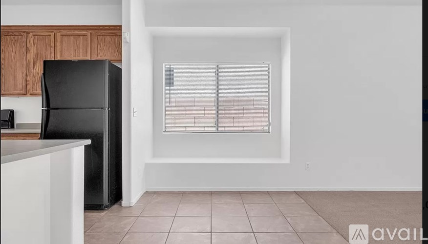 A kitchen with a black fridge and a window with blinds.