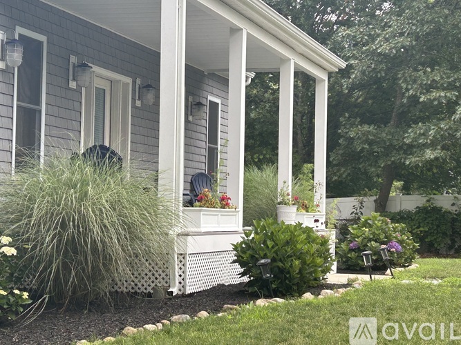 A porch with a white railing and a white bench with flowers on it.