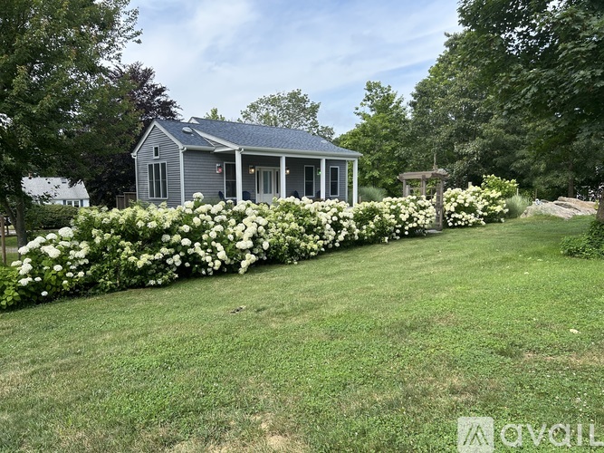 A house with a blue roof and white flowers in front.