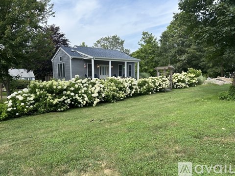 A house with a blue roof and white flowers in front.