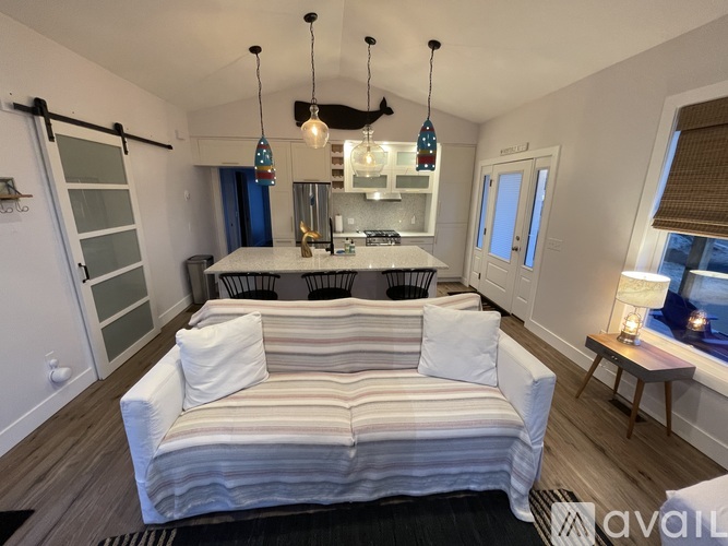 A living room with a striped couch and a kitchen area in the background.