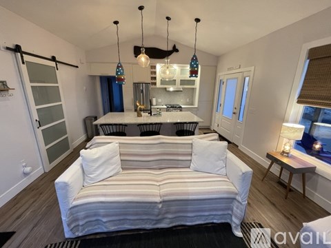 A living room with a striped couch and a kitchen area in the background.