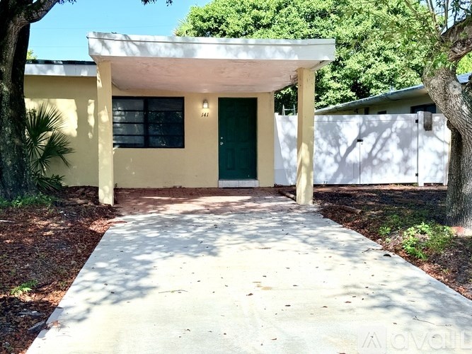 A yellow house with a green door and a white fence.