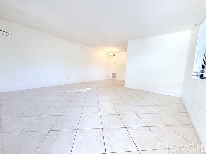 A large empty room with white walls and tiled flooring.