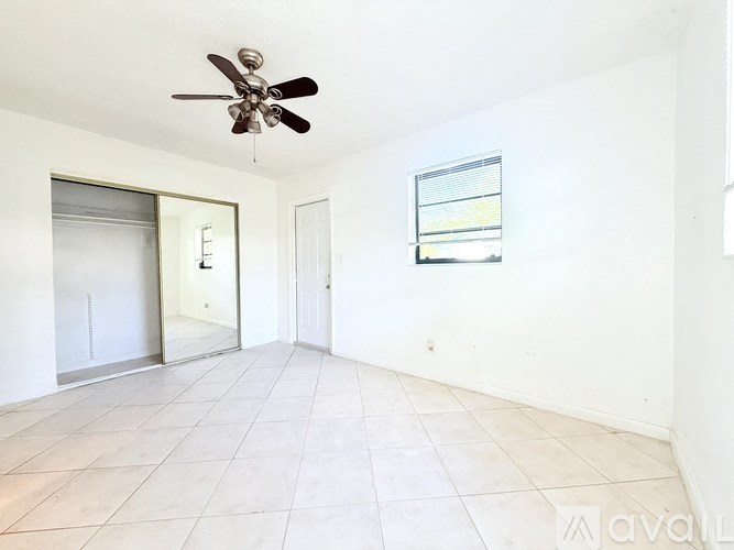 A room with a ceiling fan and a window with blinds.