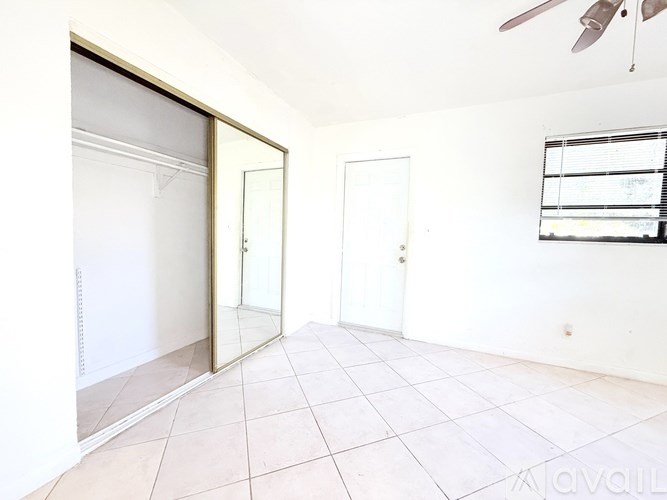 A room with a ceiling fan and a window with blinds.