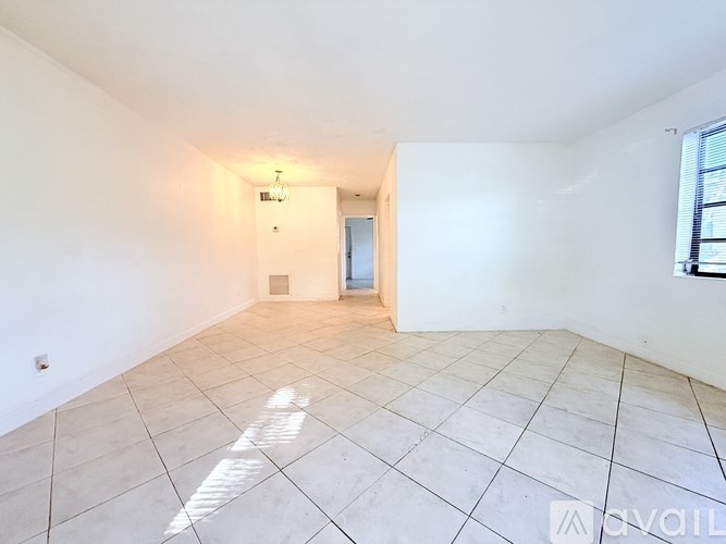 A spacious room with white walls and tiled flooring.
