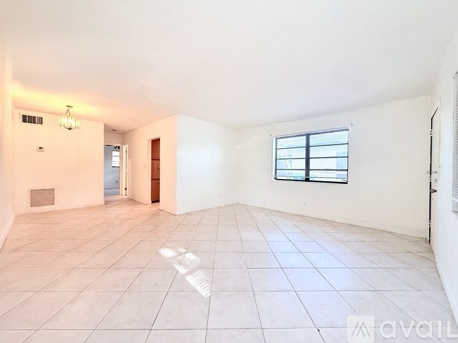 A spacious empty room with a window and tiled floor.