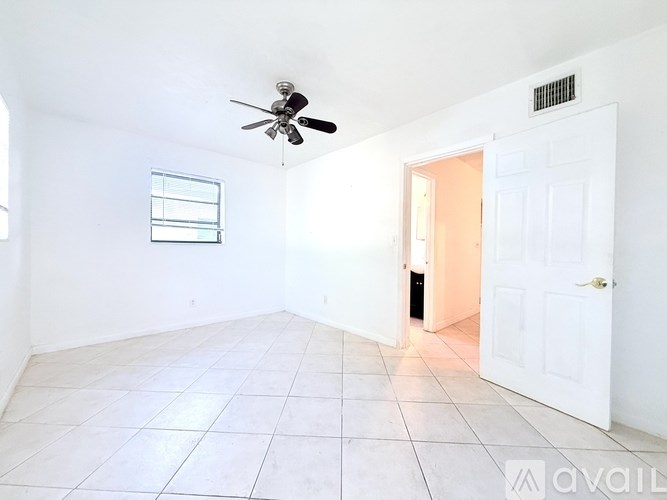 A room with a ceiling fan and a door leading to another room.