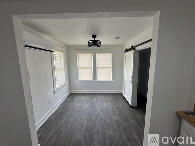 A room with a ceiling fan and two windows.