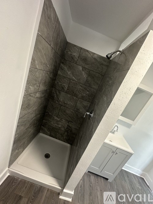 A bathroom with a tiled shower area and a white sink.