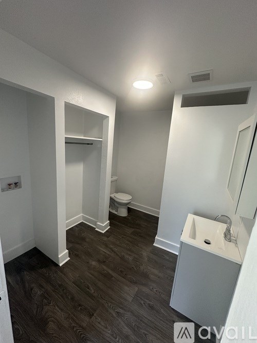 A bathroom with a toilet, sink, and mirror.