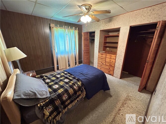 A bedroom with a bed, a ceiling fan, and a window with curtains.