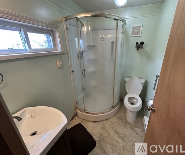 A bathroom with a glass shower stall and a toilet.