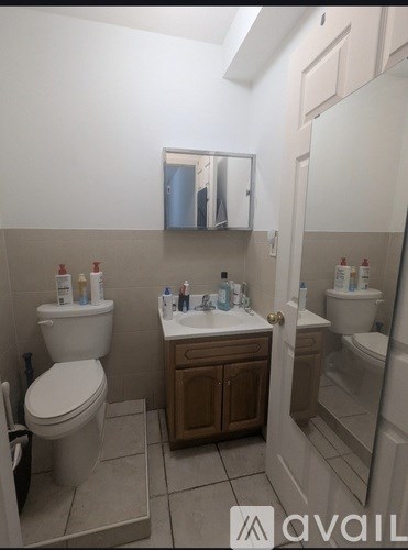 A bathroom with a toilet, sink, and mirror.