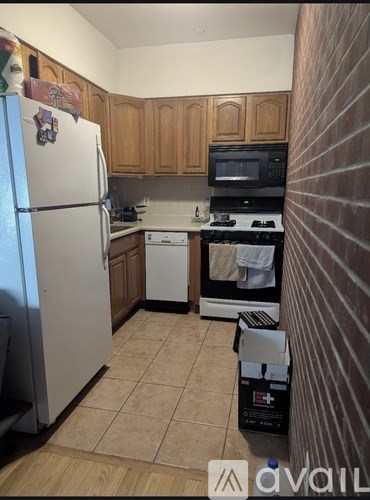 A kitchen with a white refrigerator, wooden cabinets, a black microwave, a white dishwasher, and a white stove.