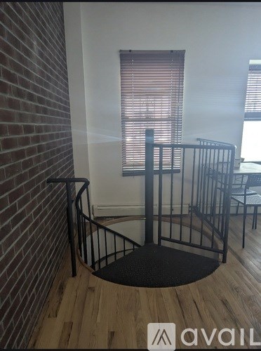A staircase with a black metal railing and wooden steps leading to a window with blinds.