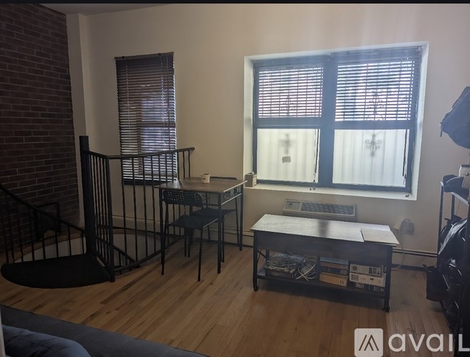 A room with a black table and chairs, a window with blinds, and a brick wall.