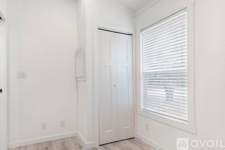A white door is in a room with a window covered in blinds.